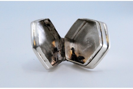  Caixa de comprimidos em prata de forma hexagonal com motivos vegetalistas gravados na tampa basculante.